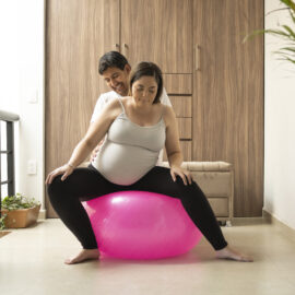 Pregnant lady on an exercise ball with partner support