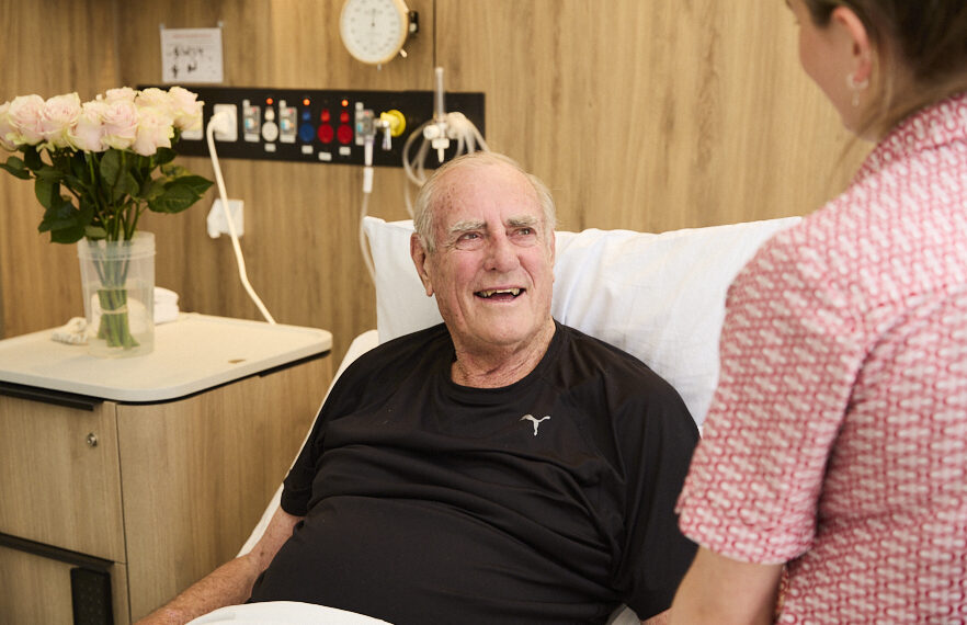 Cabrini nurse speaking with male patient in bed