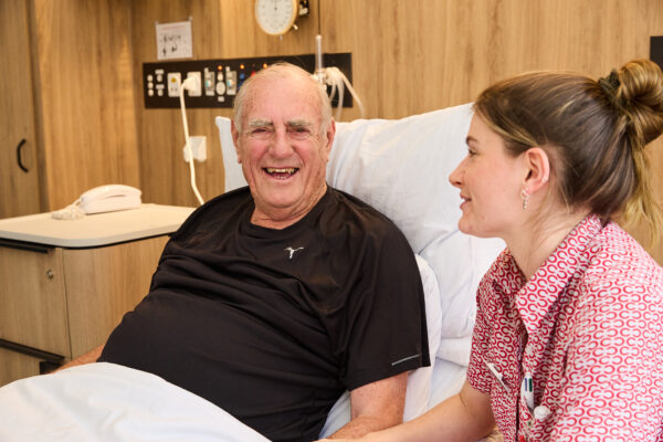 Male patient in bed and female nurse sitting beside