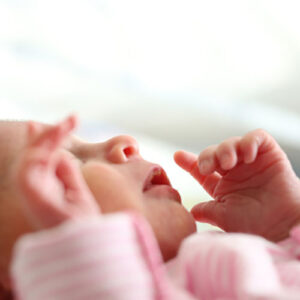 new born baby face with hands in air