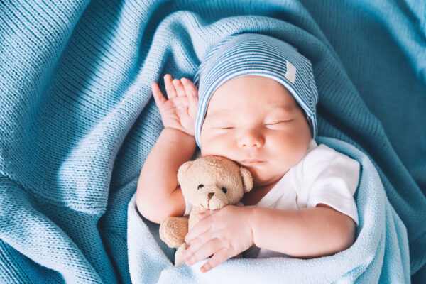 Newborn baby sleep holding a small teddy bear