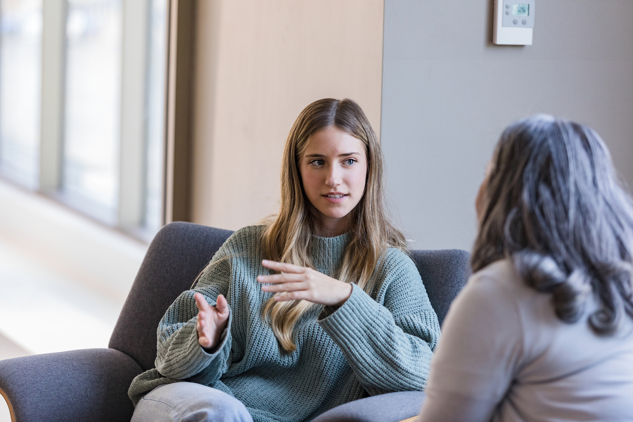 Two women sitting on a couch have a chat